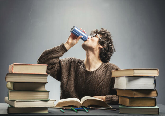Young man drinking energy drink while studying. College student concept. Energizing before learning.