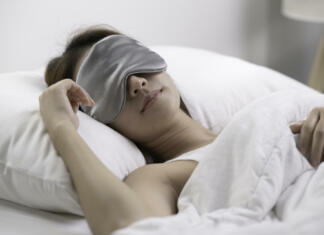 Zakaj ljudje spimo manj kot drugi primati? Ženska spi v postelji