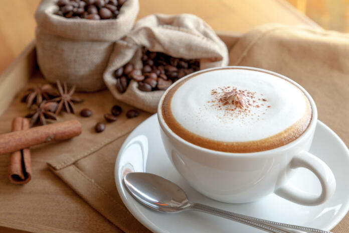 A cup of cappuccino with coffee beans