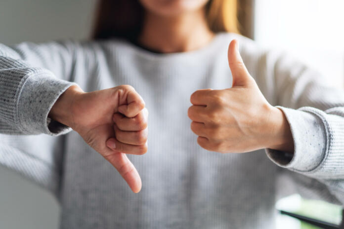 Closeup image of a woman making thumbs up and thumbs down hands sign