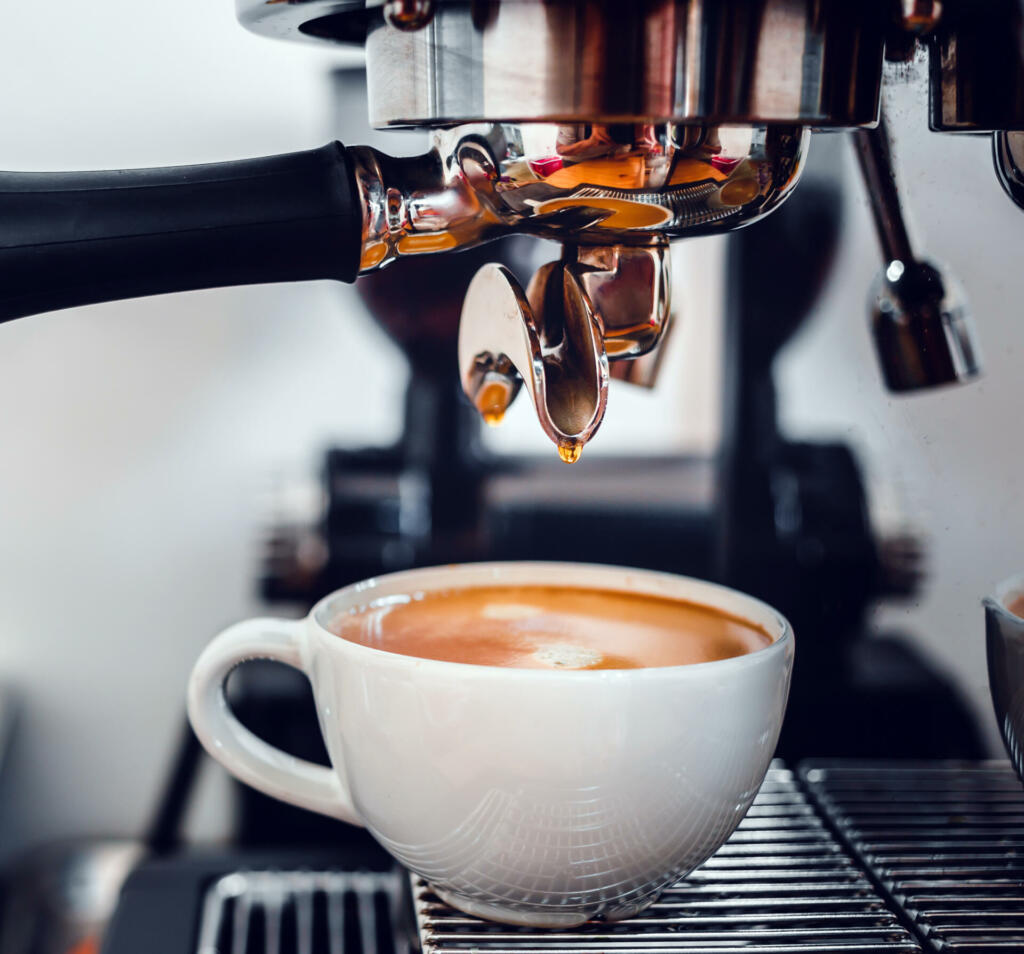 Coffee extraction from the coffee machine with a portafilter pouring coffee into a cup,Espresso poruing from coffee machine at coffee shop