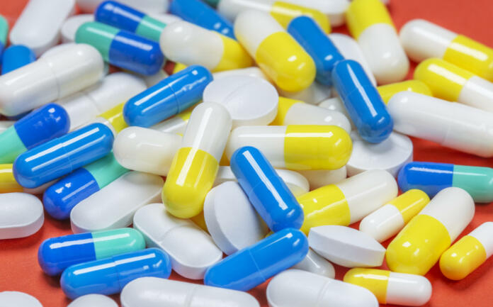 Colored pills, pills and capsules on a red background