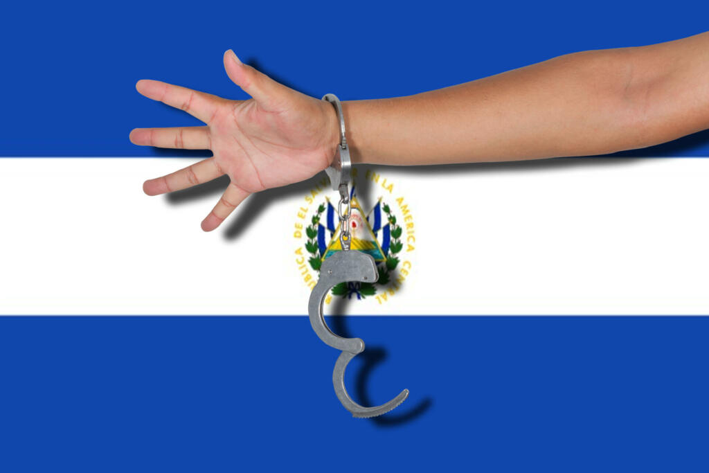 handcuffs with hand on El Salvador flag.