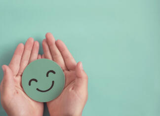 10 najsrečnejših držav na svetu! Hands holding green happy smile face paper cut, good feedback rating and positive customer review, experience, satisfaction survey ,mental health assessment, child wellness,world mental health day concept