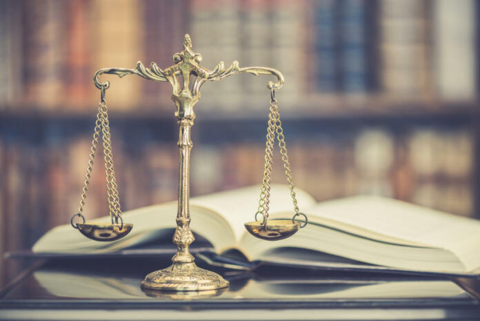 Legal office of lawyers, justice and law concept : Judge gavel or a hammer and a base used by a judge person on a desk in a courtroom with blurred weight scale of justice, bookshelf background behind.