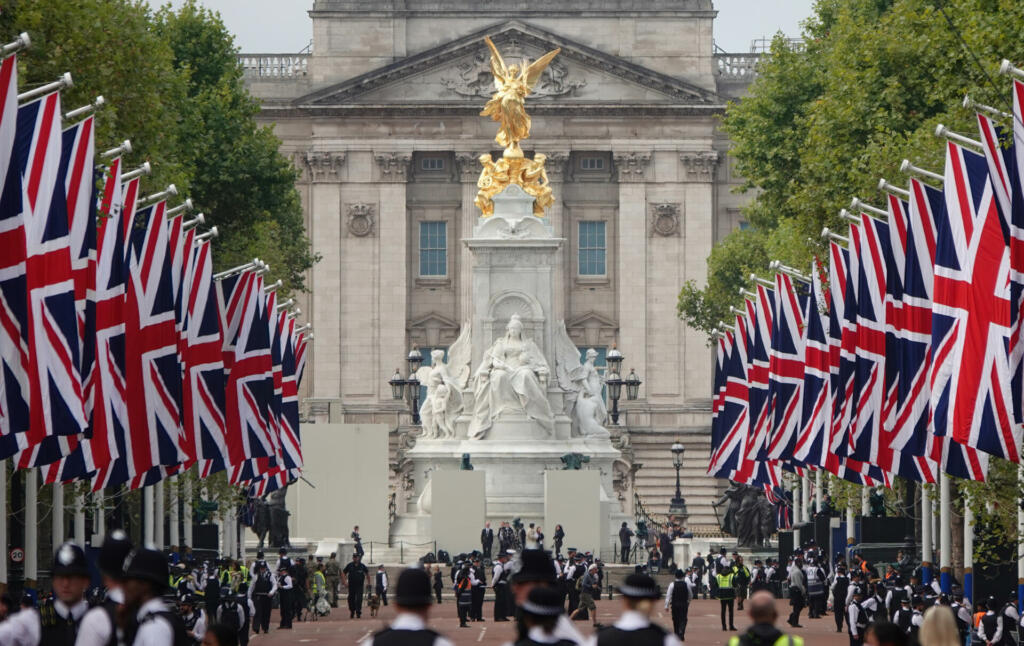 London, UK - September 14, 2022: A view of Buckingham Palace along the Mall lined with British flags on each side and police on duty to control the crowds.