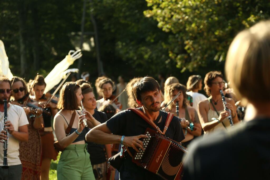 Glasbeniki, ki se pripravljajo na nastop z glasbili v rokah, pod drevesom.