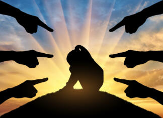 Kdo bi se moral boriti proti nasilju v šolah? Peers' hands show with their fingers a sad and frightened child girl against the sunset. Conceptual image of bullying children