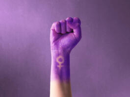 Raised purple fist of a woman for international women's day and the feminist movement. March 8 for feminism, independence, freedom, empowerment, and activism for women rights