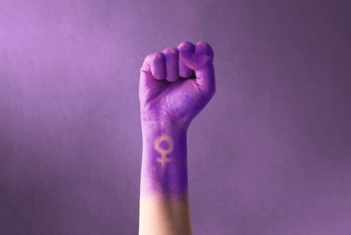 Raised purple fist of a woman for international women's day and the feminist movement. March 8 for feminism, independence, freedom, empowerment, and activism for women rights