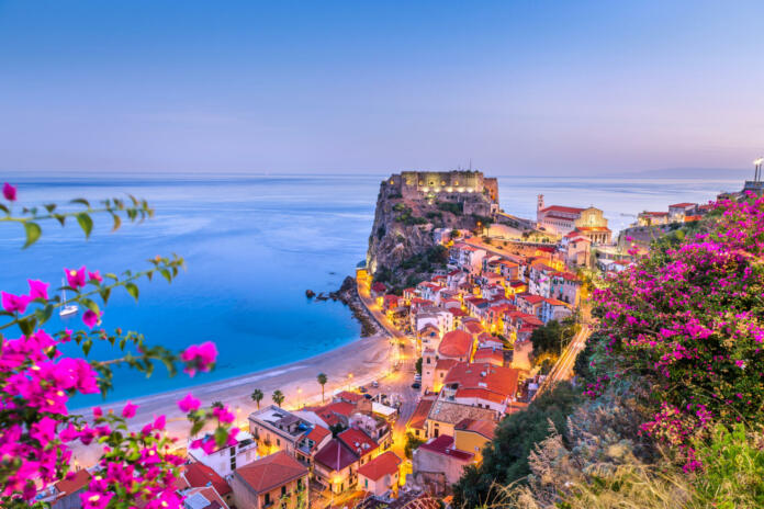 Scilla, Italy on the Mediterranean coast at twilight with seasonal flowers.