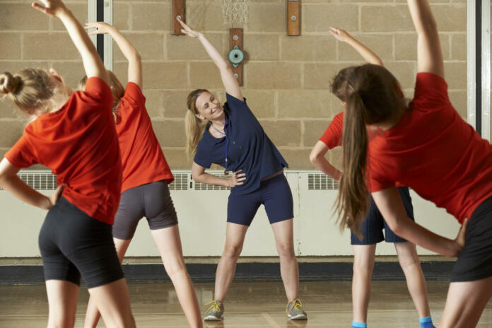 Teacher Taking Exercise Class In School Gym