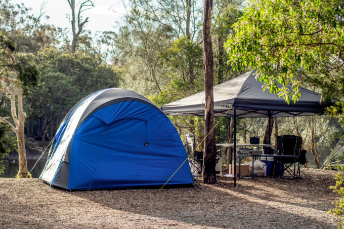 Tent setup with gazebo canopy shelter at the campsite surrounding by nature on the river bank. Camping and recreation