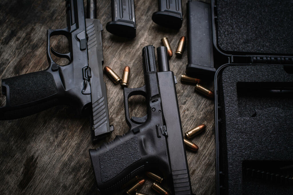 Two 9mm pistols hold slides on a wooden table. 