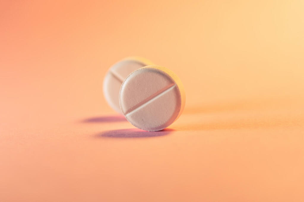 Two pills in an orange-pink background. Medical theme. Selective focus.