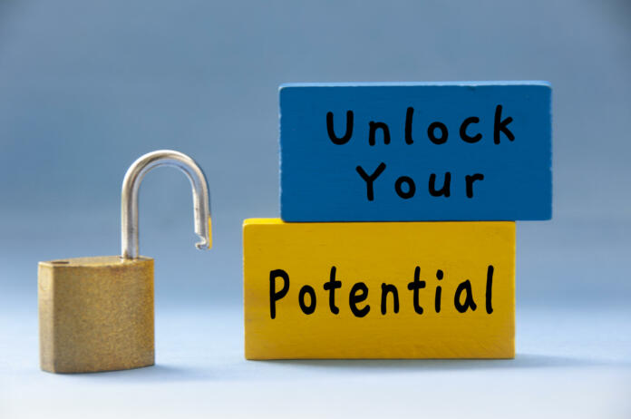Unlock your potential text on wooden blocks with pad lock on light blue background. Motivational concept