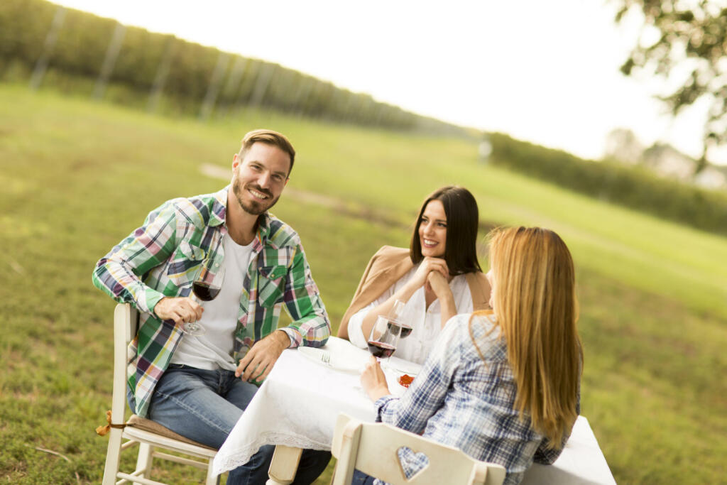 Young people enjoy dinner and wine tasting in the vineyard