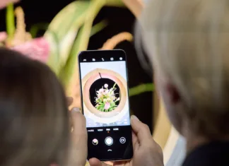 Zaslon, ki bo prepričal tudi največje dvomljivce Roka drži telefon, na obeh straneh se vidita glavi