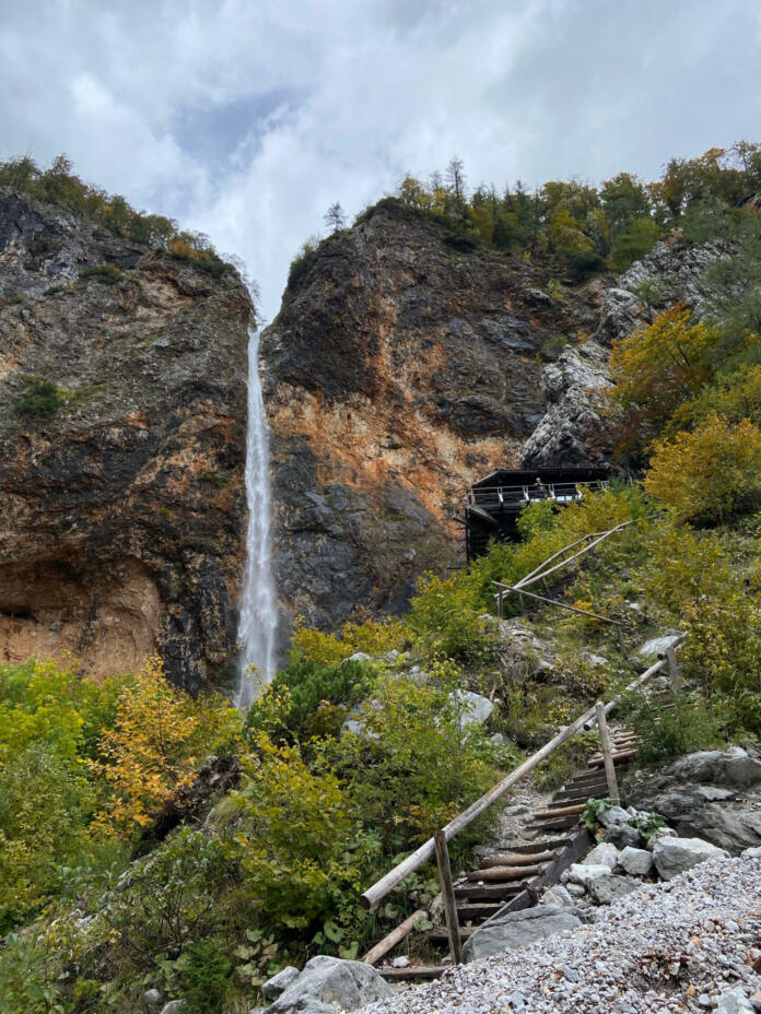 A beautiful vertical shot of the Rinka waterfall in Slovenia with a stairway leading up to it under a cloudy sky