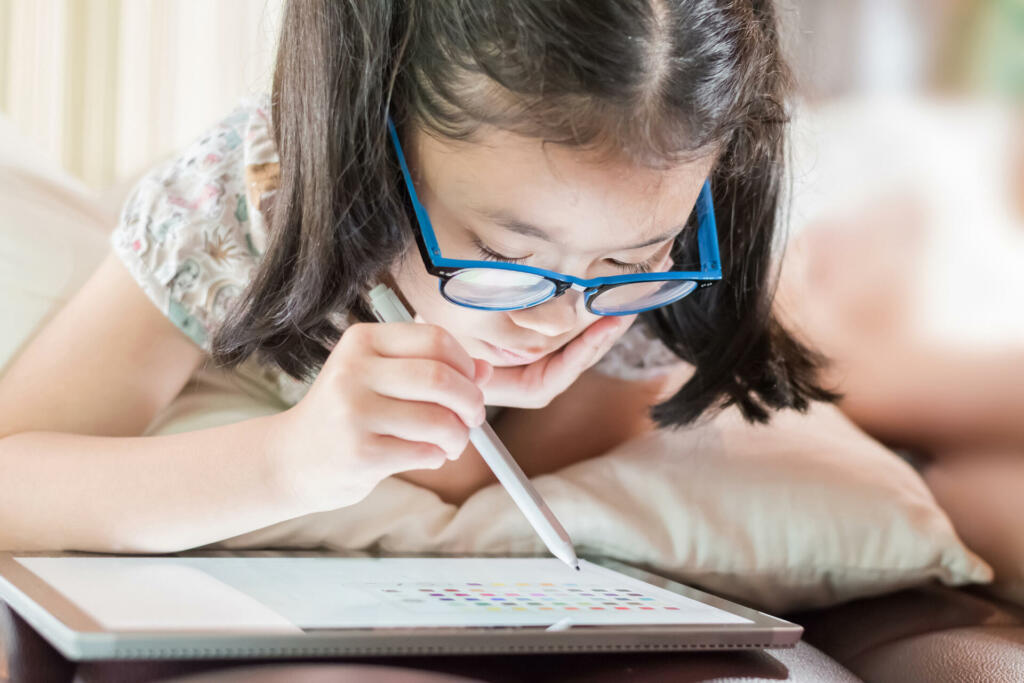 Asian school child girl using smart tablet device digital technology drawing on innovative touchscreen surface