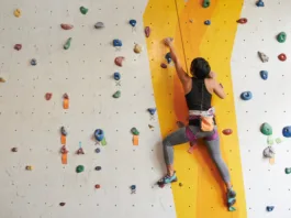 Athletic woman climbing indoors, view from the back