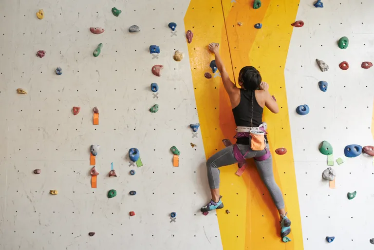 Athletic woman climbing indoors, view from the back