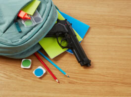 Backpack, school supplies and gun on desk