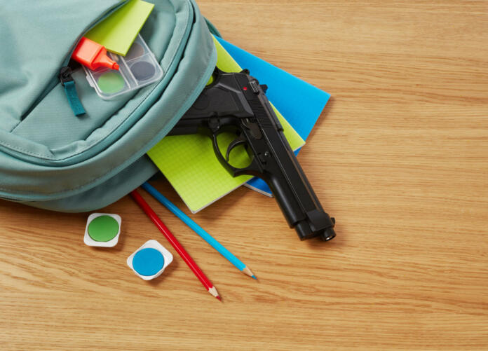 Backpack, school supplies and gun on desk