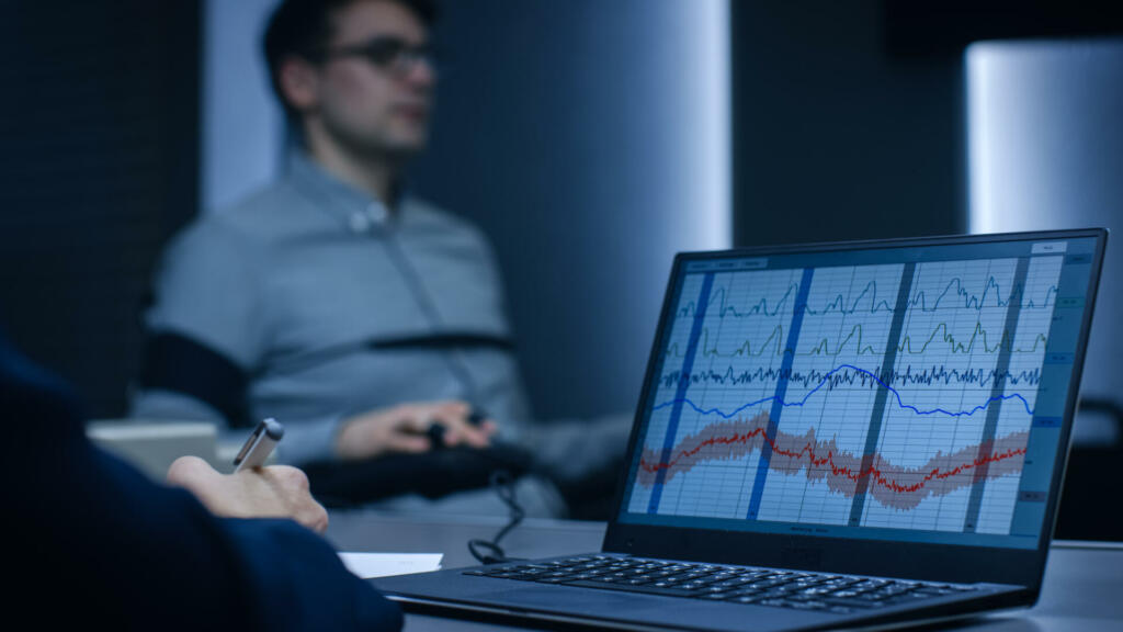 Computer Shows Physiological Measures of a Man Undergoing Lie Detector / Polygraph Test. Examining Expert Writes Down Observations.