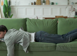 Bi si moral privoščiti popoldanski počitek? Exhausted young man came home after work flopped down on sofa.