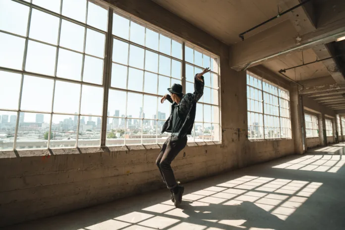 oseba pleše v betonskem prostoru z velikimi okni