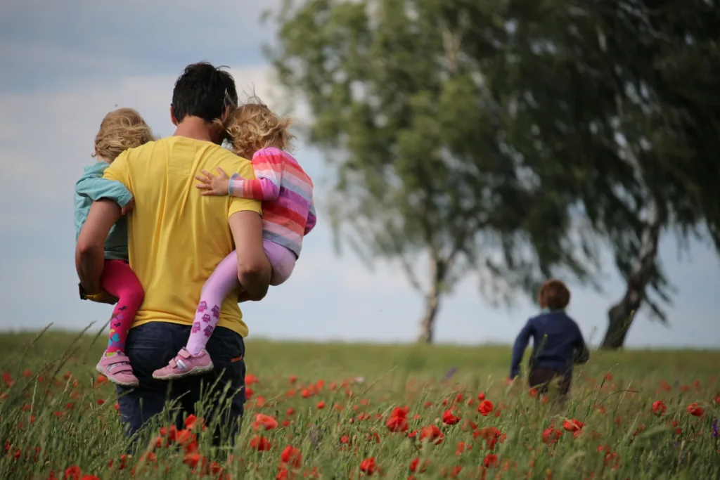 Moški na polju nosi dve deklici