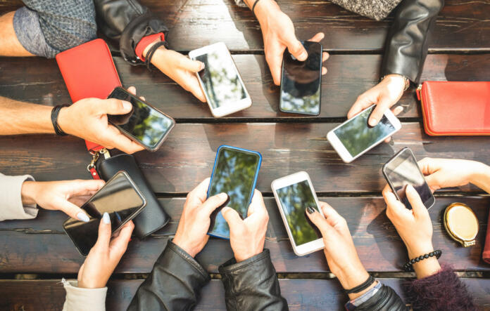 People group having addicted fun together using smartphones - Detail of hands sharing content on social network with mobile smart phones - Technology concept with millennials online with cellphones