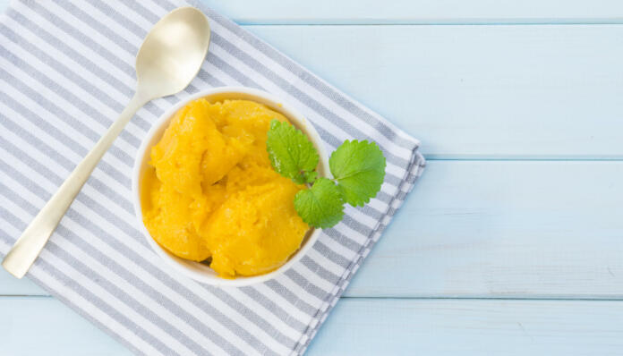 Portion of mango ice cream garnished with a sprig of mint