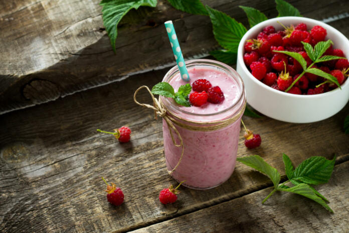 Raspberry fruit Yogurt smoothie or milk shake in glass jar on a wooden rustic table. Natural detox, fruit dessert, healthy dieting concept. Copy space.