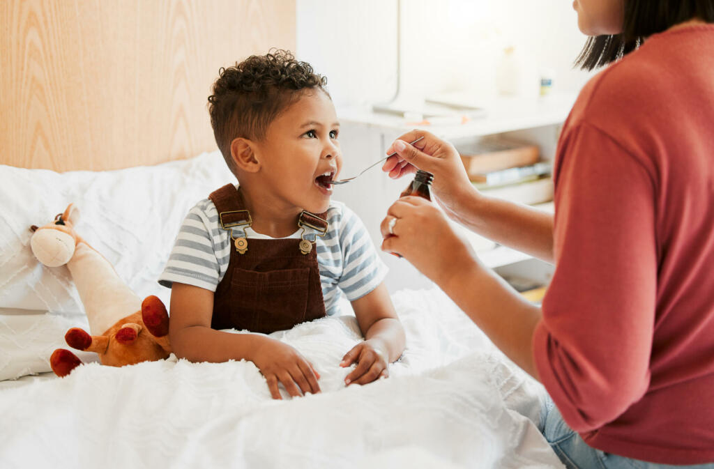 Sick child taking medicine syrup, flu treatment and cold cure for illness, sickness and virus symptoms. Mom caring for health of little son, kid and boy to rest, recover and get better in bed at home