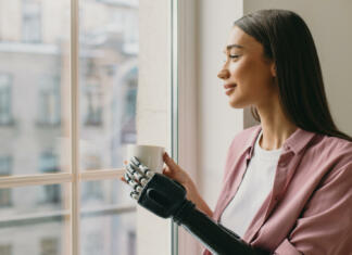 Odkritje, ki bo spremenilo svet protetike Side view of beautiful lovely female with long brown hair standing in front of window with coffee in hands, watching her boyfriend returning home, having iron biotechnological arm prosthesis