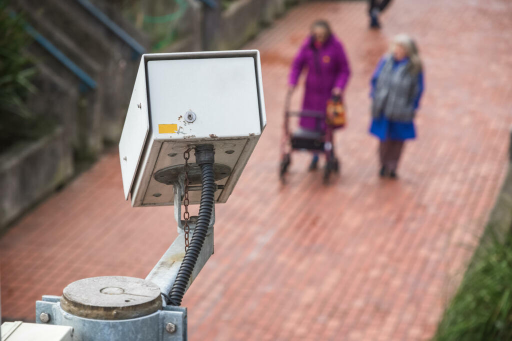 Surveillance camera with unidentified walking elderly people in the background in London
