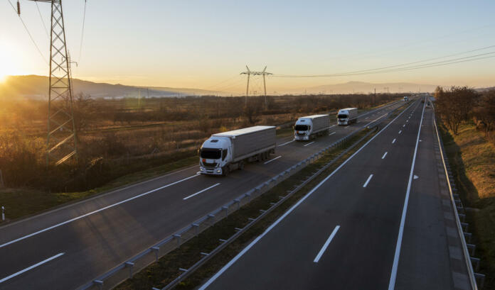 Transportation trucks passing by on a country highway under a beautiful sky. Business Transportation And Trucking Industry.