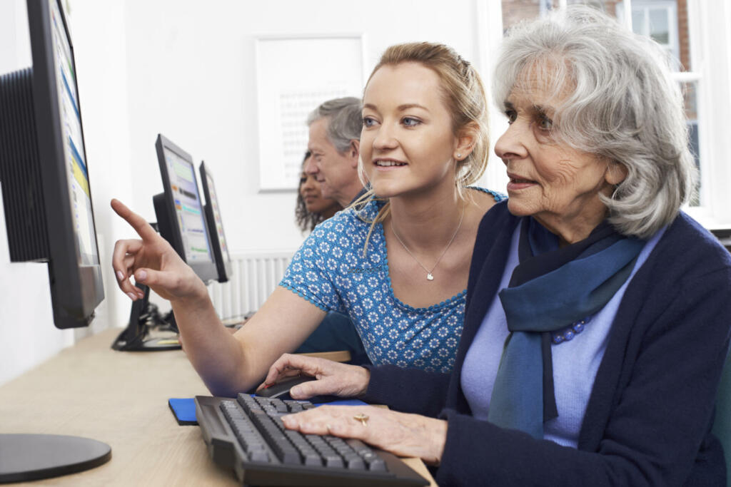 Tutor Helping Senior Woman In Computer Class