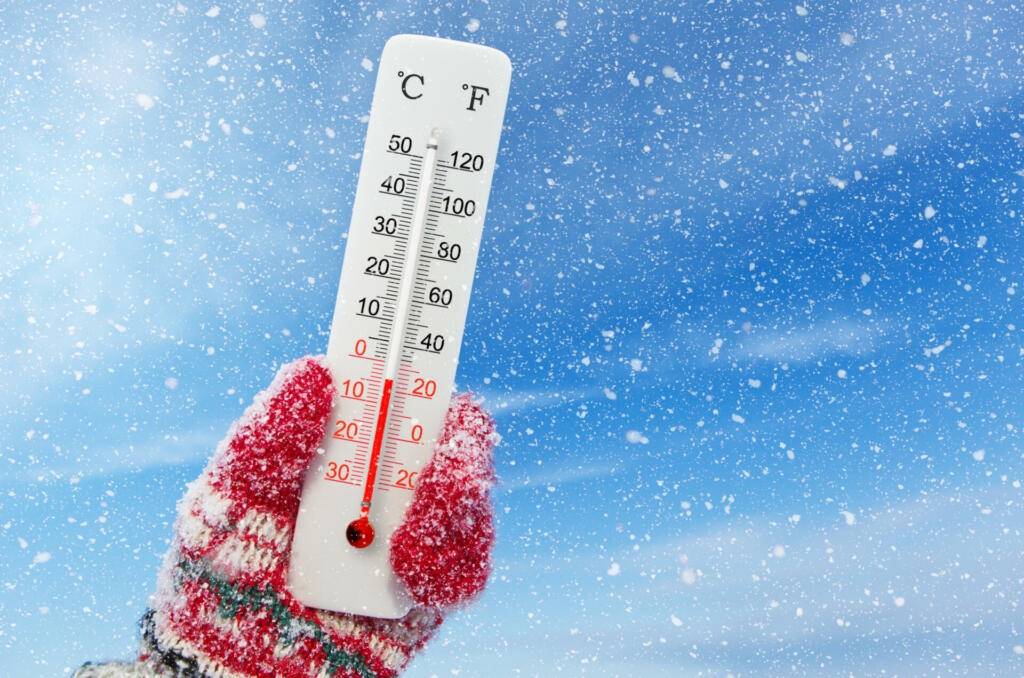 White celsius and fahrenheit scale thermometer in hand. Ambient temperature minus 4 degrees celsius