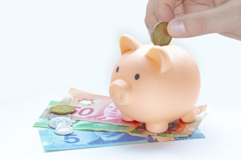 A person saving Canadian currency. Canadian Bill and coin on a white background. Concept: Saving money