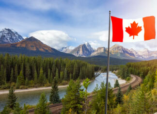 Delovne počitnice v Kanadi: Živi in delaj z International Experience Canada Canadian National Flag composite with Rocky Mountain Landscape in background. Fall Season Sunny Sky. Lake Louise, Banff National Park, Alberta, Canada.
