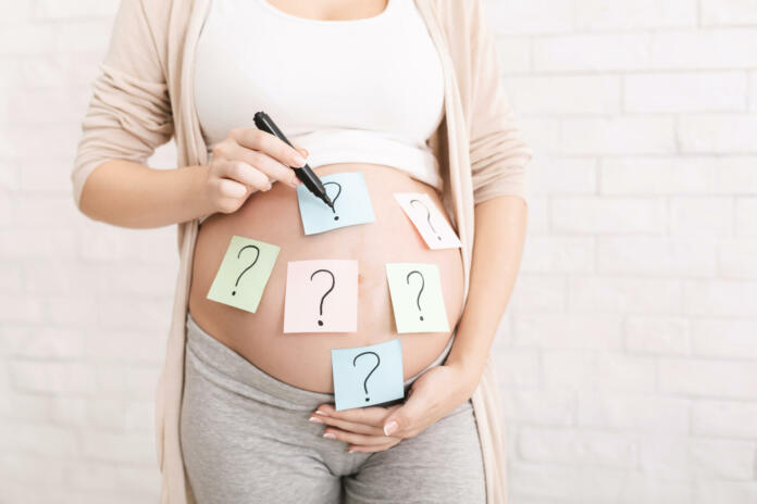 Choosing baby name. Pregnant woman embracing her belly with question mark on it, panorama with free space