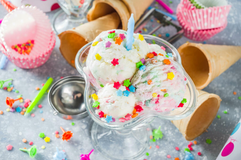 Colorful Birthday cake ice cream with Birthday decoration and ice cream waffle cones, white gray background copy space
