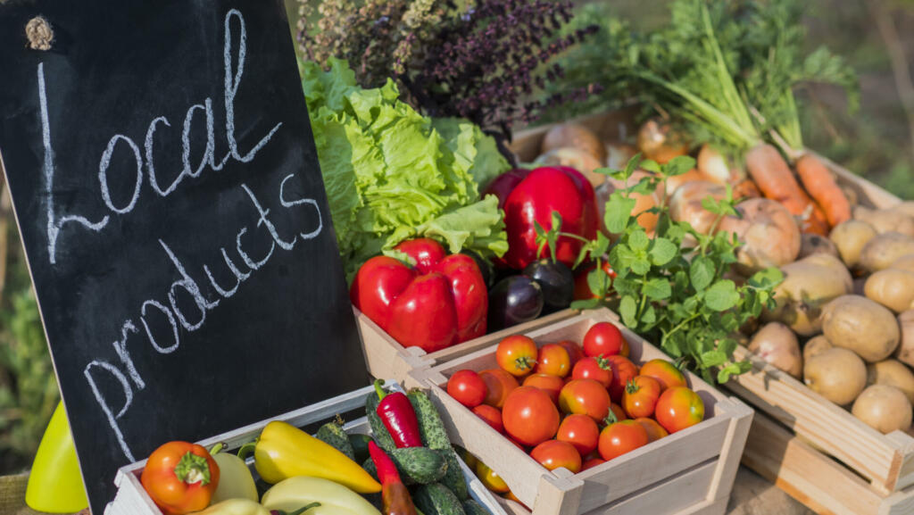 Counter with fresh vegetables and a sign of local products.