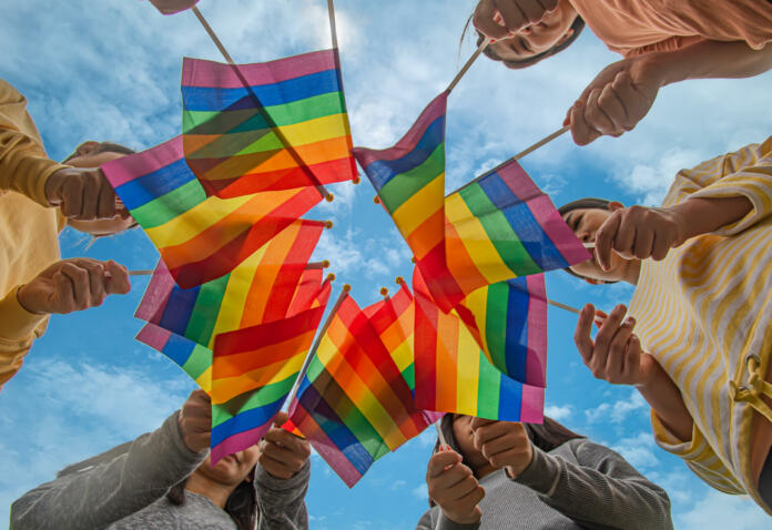 Diversity people hands raising colorful lgbtq rainbow flags together , a symbol for the LGBT community
,selective focus.concept LGBTQ community equal movement parade ,LGBTQ pride month.