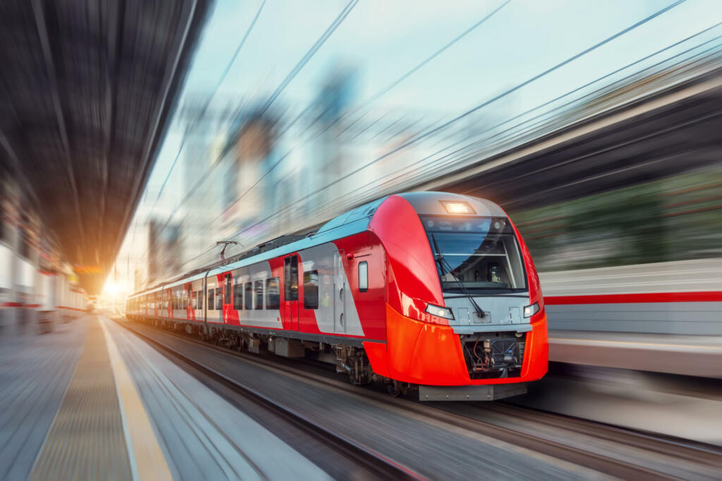 Electric passenger train drives at high speed among urban landscape