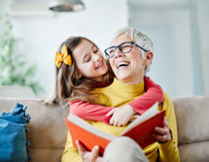 Grandmother and granddaughter having fun together and reading a book at home