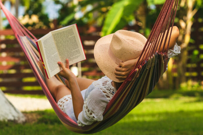 Happy beautiful woman in white dress relaxing in hammock.